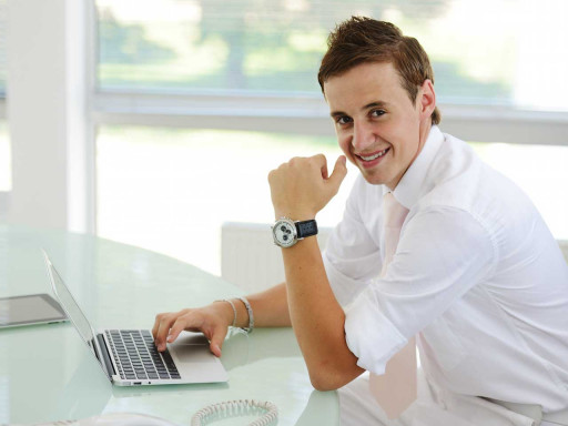 Young man sat at a desk with a laptop.