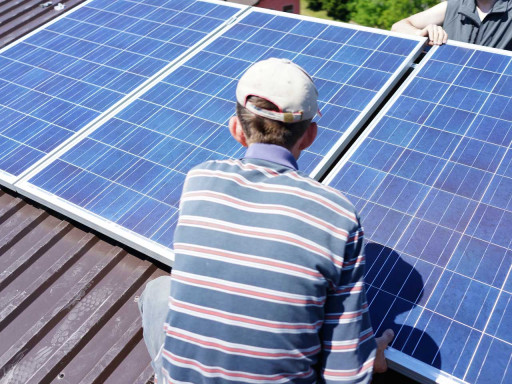 Man working on roof installing solar panel.