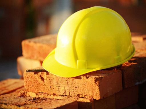 Yellow hard hat on bricks.