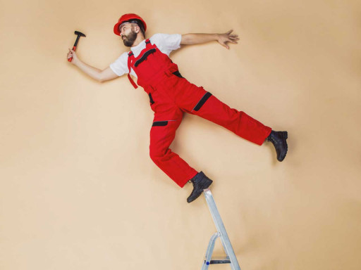 Man standing on top of a stepladder with a hammer.