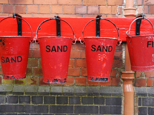 Several sand buckets hanging on wall.